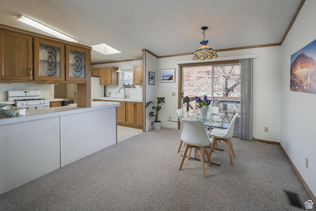 carpeted dining space featuring crown molding, a skylight, sink, and a textured ceiling