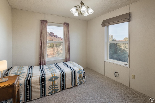 carpeted bedroom featuring multiple windows, a mountain view, a textured ceiling, and a chandelier