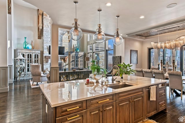 9632 N 5650 W, Highland, UT 84003 - kitchen featuring decorative light fixtures, sink, dark hardwood / wood-style flooring, a kitchen island with sink, and light stone countertops