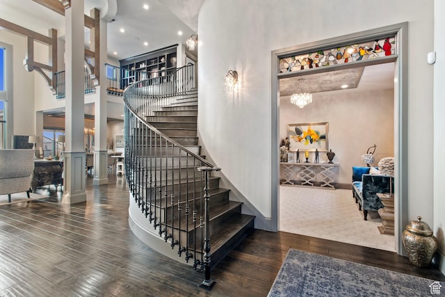 9632 N 5650 W, Highland, UT 84003 - staircase featuring hardwood / wood-style flooring, a towering ceiling, a notable chandelier, and ornate columns