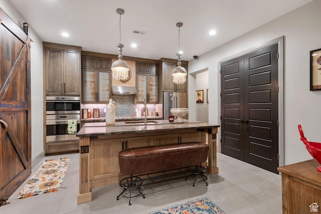 9632 N 5650 W, Highland, UT 84003 - kitchen with a breakfast bar, pendant lighting, stainless steel appliances, a barn door, and a center island with sink