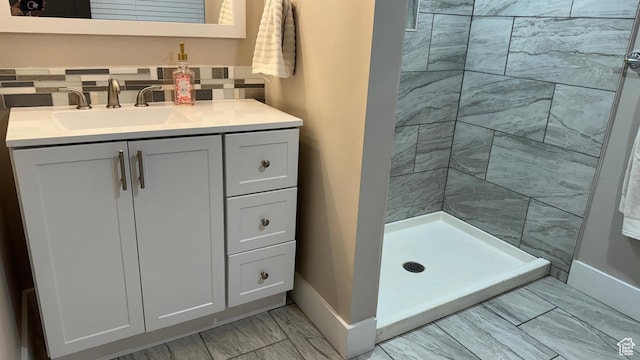 bathroom featuring a tile shower, vanity, and backsplash