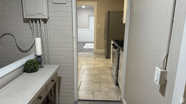 bathroom featuring brick wall and tile patterned floors