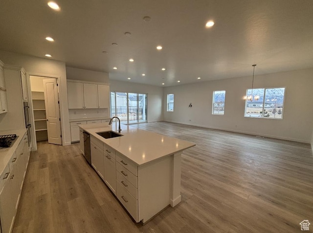 284 E Polaris Dr Unit 112, Saratoga Springs, UT 84045 - kitchen with decorative light fixtures, white cabinetry, an island with sink, sink, and light hardwood / wood-style flooring