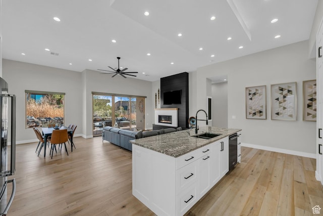 2090 N Tuweap Dr Unit 56, St George, UT 84770 - kitchen with sink, dark stone countertops, a fireplace, an island with sink, and white cabinets