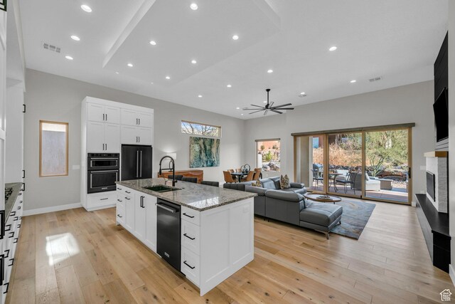 2090 N Tuweap Dr Unit 56, St George, UT 84770 - kitchen with sink, white cabinets, light stone counters, black appliances, and a center island with sink