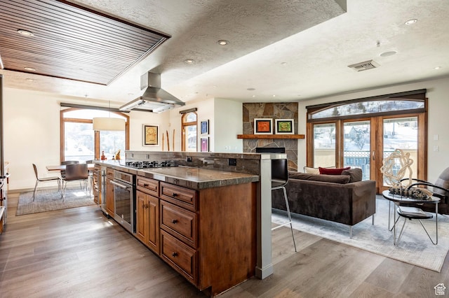 751 Main St Unit 415, Park City, UT 84060 - kitchen with appliances with stainless steel finishes, a breakfast bar, island range hood, a stone fireplace, and light hardwood / wood-style floors