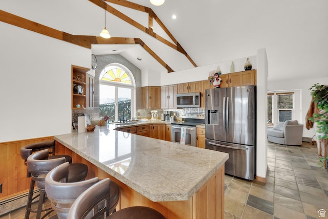 kitchen with appliances with stainless steel finishes, decorative light fixtures, a kitchen bar, a baseboard heating unit, and kitchen peninsula