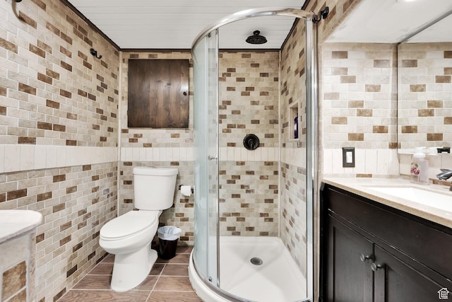 bathroom with a shower with door, vanity, tile walls, and tile patterned floors