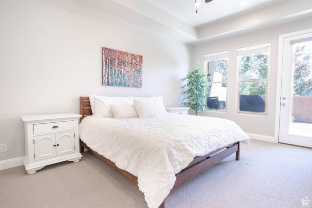 bedroom featuring access to exterior, light colored carpet, a raised ceiling, and ceiling fan