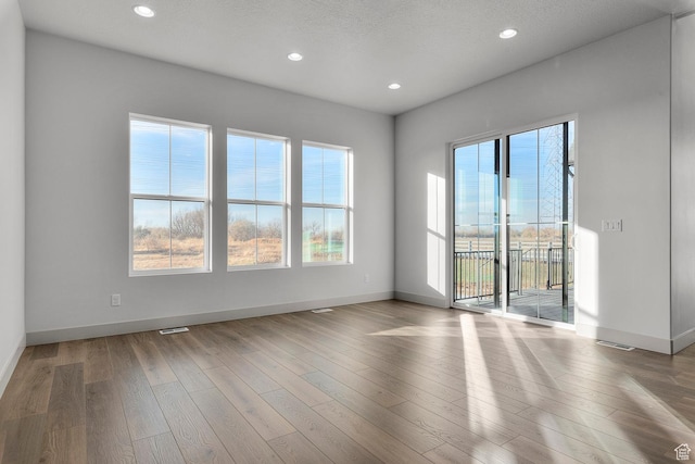 spare room featuring a textured ceiling and light wood-type flooring