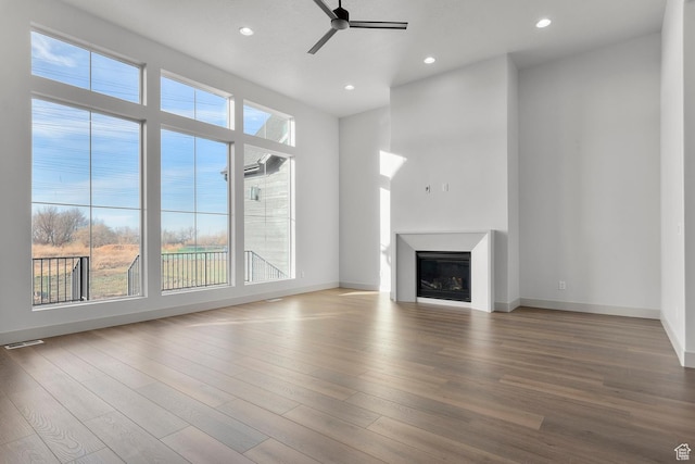 unfurnished living room with hardwood / wood-style flooring, a wealth of natural light, and ceiling fan