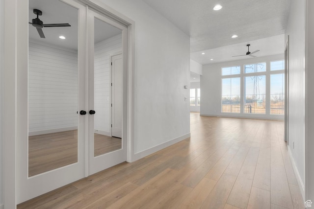 empty room with a textured ceiling, french doors, ceiling fan, and light wood-type flooring