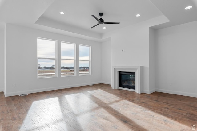 1137 W 2275 S, Syracuse, UT 84075 - unfurnished living room with ceiling fan, a tray ceiling, and light hardwood / wood-style floors