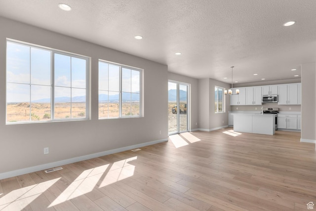 541 W Coyote Ridge Rd, Grantsville, UT 84029 - unfurnished living room with an inviting chandelier, a mountain view, light hardwood / wood-style flooring, and a textured ceiling