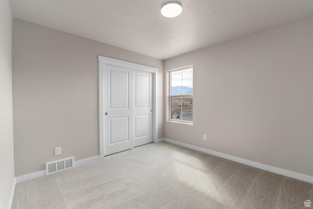 541 W Coyote Ridge Rd, Grantsville, UT 84029 - unfurnished bedroom with light carpet, a textured ceiling, and a closet