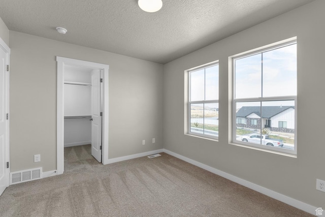 541 W Coyote Ridge Rd, Grantsville, UT 84029 - unfurnished bedroom with a closet, a spacious closet, light carpet, and a textured ceiling