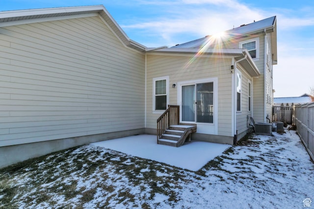 snow covered back of property with central AC