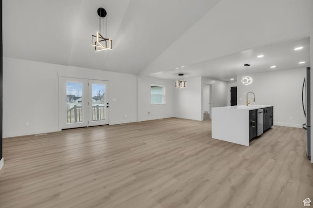 unfurnished living room featuring baseboards, light wood-style floors, a sink, and an inviting chandelier