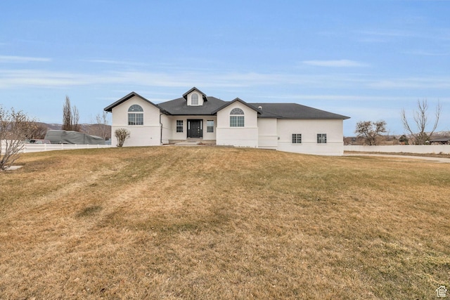 view of front of property featuring a front yard, stucco siding, and fence