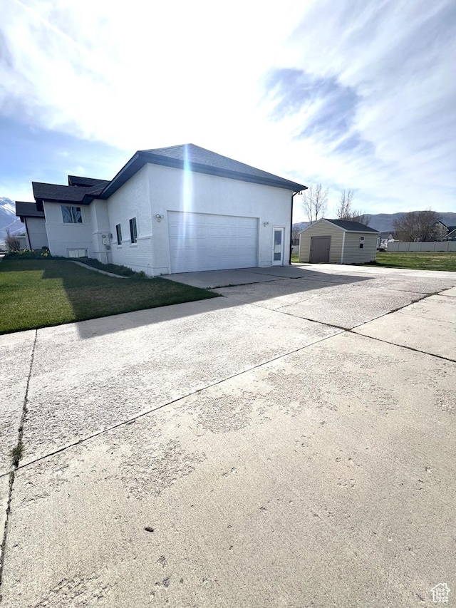 view of side of home with concrete driveway, a garage, a lawn, and stucco siding