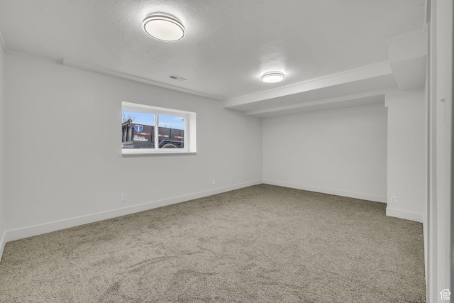 below grade area featuring visible vents, a textured ceiling, baseboards, and carpet floors