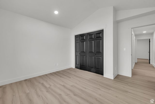 unfurnished bedroom featuring wood finished floors, baseboards, and vaulted ceiling