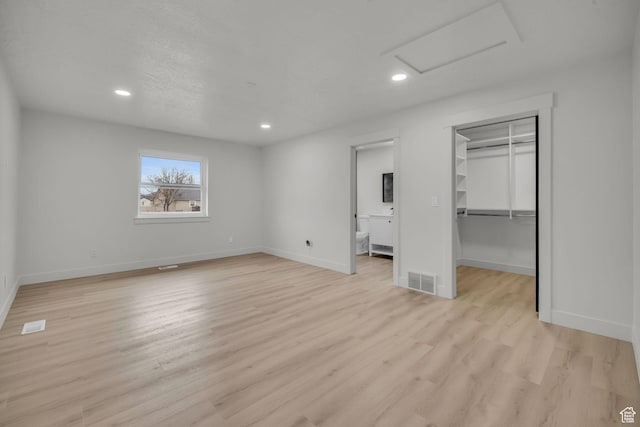 unfurnished bedroom with baseboards, light wood-type flooring, recessed lighting, attic access, and visible vents