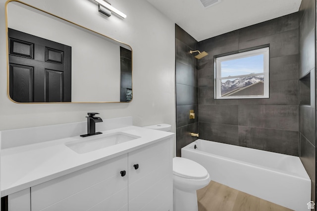 bathroom with toilet, wood finished floors, vanity, and washtub / shower combination