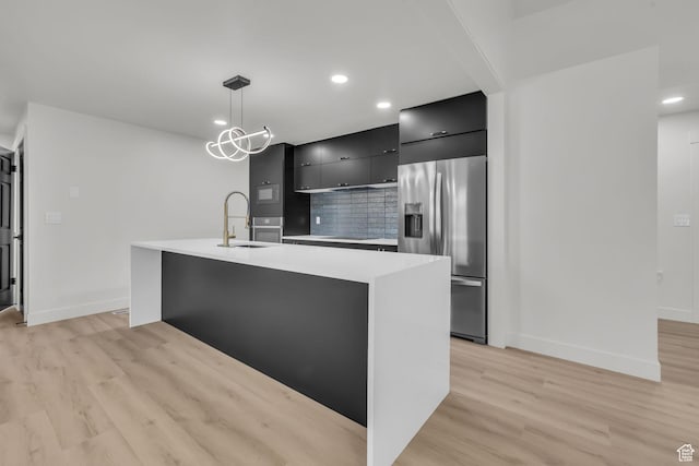 kitchen with light wood-style floors, modern cabinets, stainless steel fridge, and dark cabinets