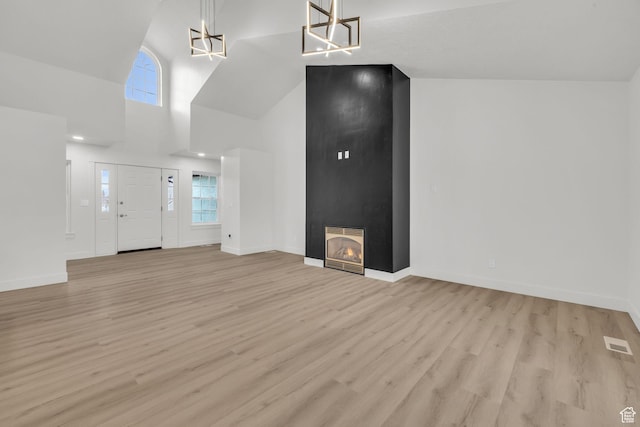 unfurnished living room featuring visible vents, heating unit, a chandelier, and light wood-style floors