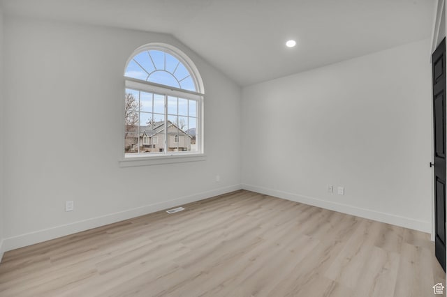 unfurnished room with light wood-type flooring, visible vents, baseboards, and lofted ceiling