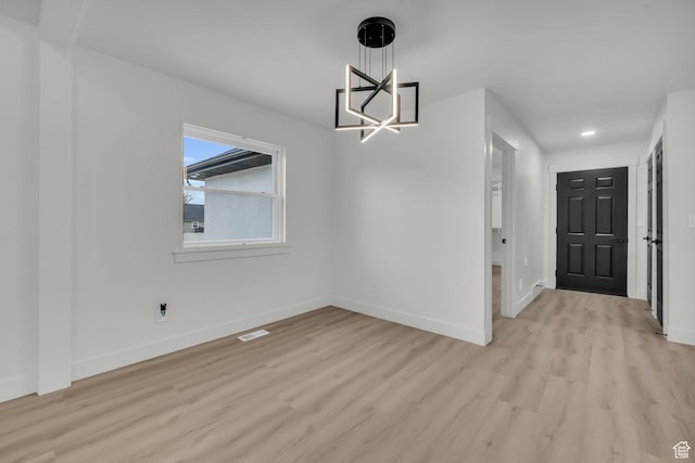 unfurnished dining area with light wood-style floors, an inviting chandelier, baseboards, and visible vents