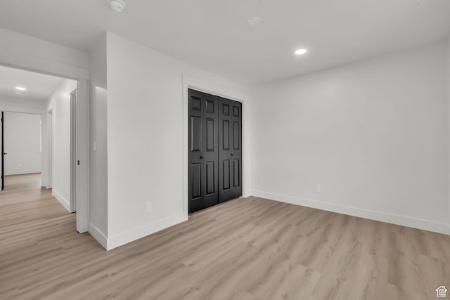 spare room with baseboards, light wood-type flooring, and recessed lighting