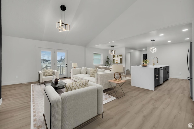 living room with high vaulted ceiling, light wood-style flooring, baseboards, and an inviting chandelier