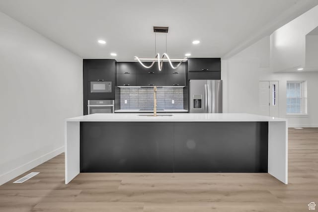kitchen featuring modern cabinets, light countertops, a sink, stainless steel appliances, and dark cabinetry