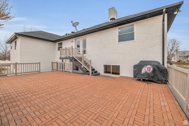 rear view of property with a patio, stucco siding, and fence
