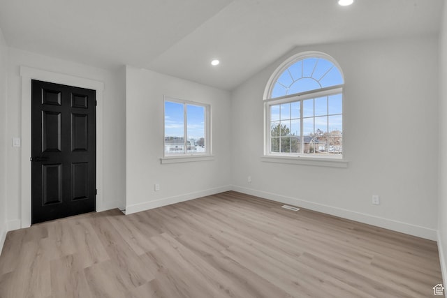 foyer with visible vents, light wood-style flooring, vaulted ceiling, and baseboards