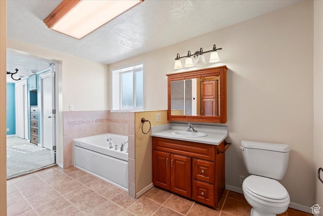 bathroom with vanity, a textured ceiling, a bathing tub, and toilet