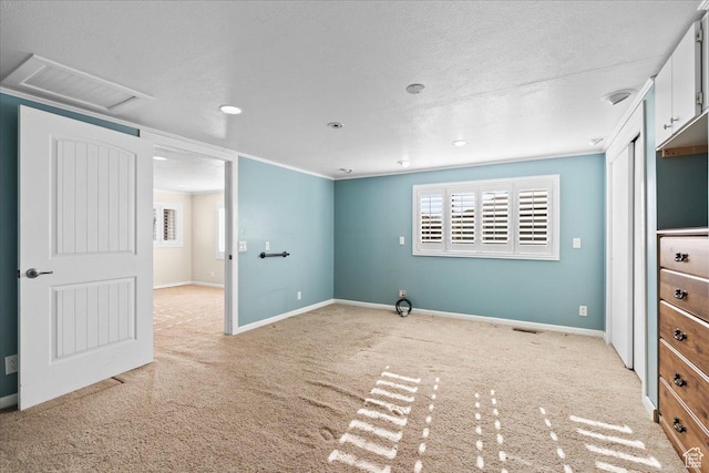 carpeted empty room featuring crown molding and a textured ceiling