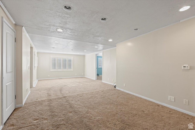 carpeted empty room featuring crown molding and a textured ceiling