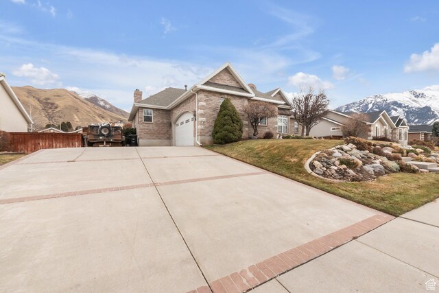 1839 E River Bottom Rd, Springville, UT 84663 - view of home's exterior featuring an attached garage, concrete driveway, a mountain view, a chimney, and brick siding