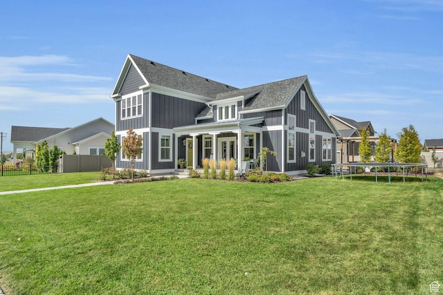 rear view of property with a trampoline and a yard