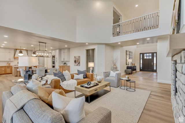 living room with baseboards, recessed lighting, light wood-style floors, and a towering ceiling