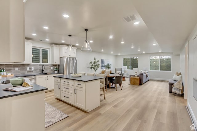 909 W 1180 N, Pleasant Grove, UT 84062 - kitchen with freestanding refrigerator, a sink, dark countertops, a breakfast bar area, and white cabinets