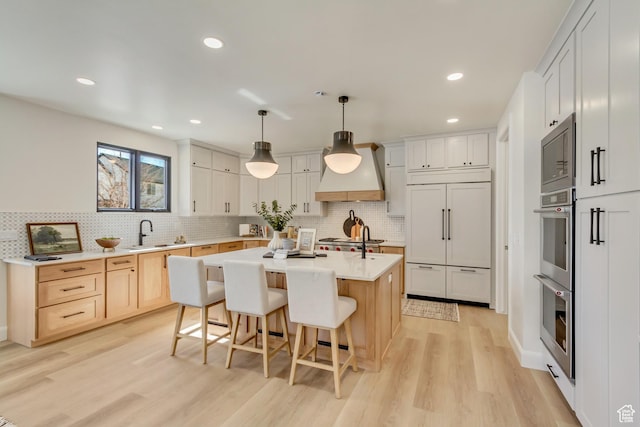 909 W 1180 N, Pleasant Grove, UT 84062 - kitchen with custom exhaust hood, built in appliances, light wood-style flooring, tasteful backsplash, and a breakfast bar