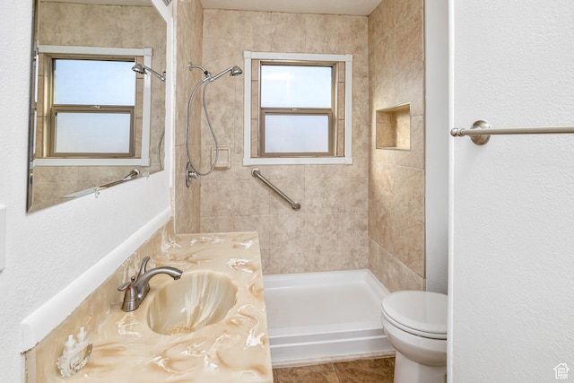 bathroom featuring vanity, tile patterned floors, toilet, and tiled shower