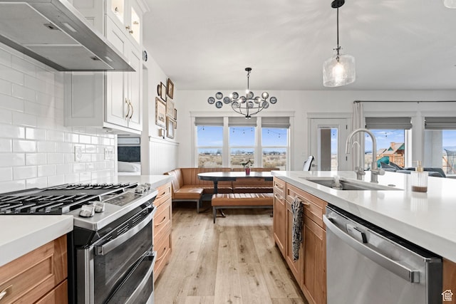 2418 W 4975 N, Cedar City, UT 84721 - kitchen featuring appliances with stainless steel finishes, white cabinetry, sink, hanging light fixtures, and exhaust hood