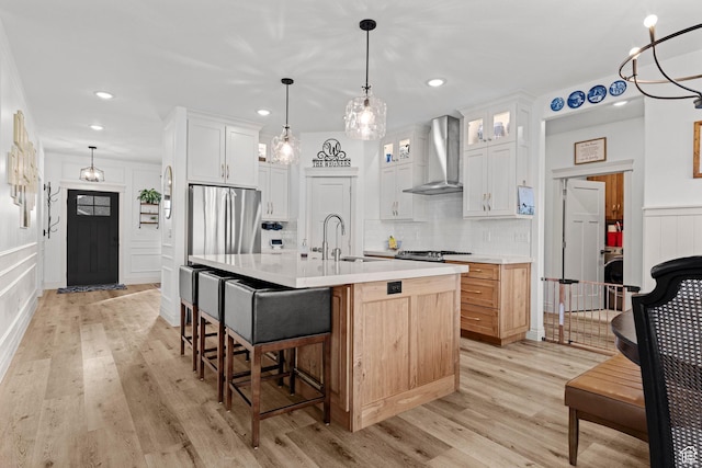 2418 W 4975 N, Cedar City, UT 84721 - kitchen featuring wall chimney range hood, sink, an island with sink, white cabinets, and decorative light fixtures