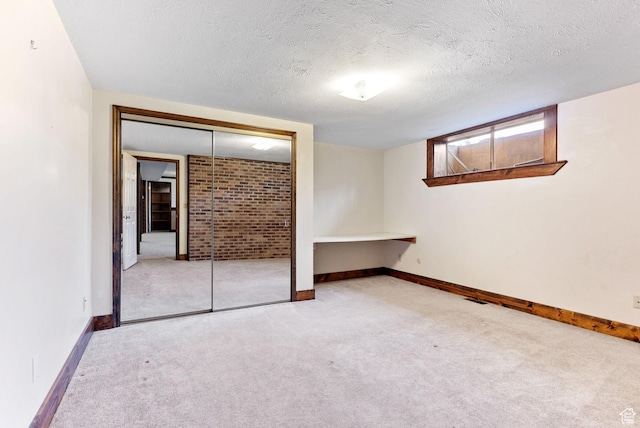 unfurnished bedroom featuring light carpet, a textured ceiling, and a closet